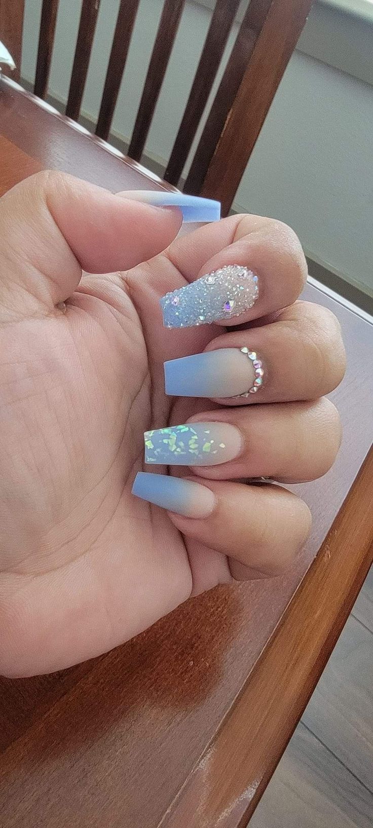 Elegant Pastel Blue Nail Design with Matte Finishes, Glitter Accents, and Ombre Effects.