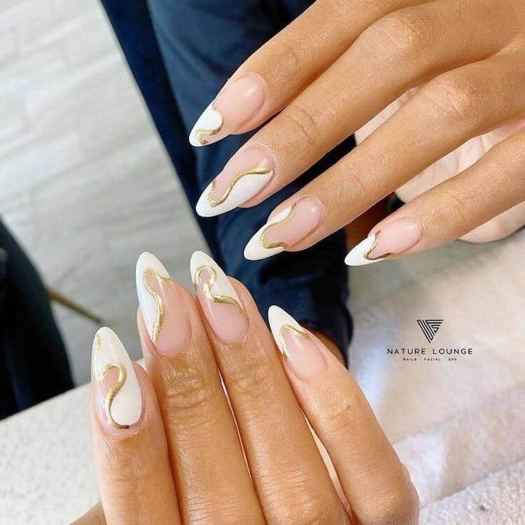 Chic Almond-Shaped Nails with Elegant Gold Detailing and Nude-White Polish.