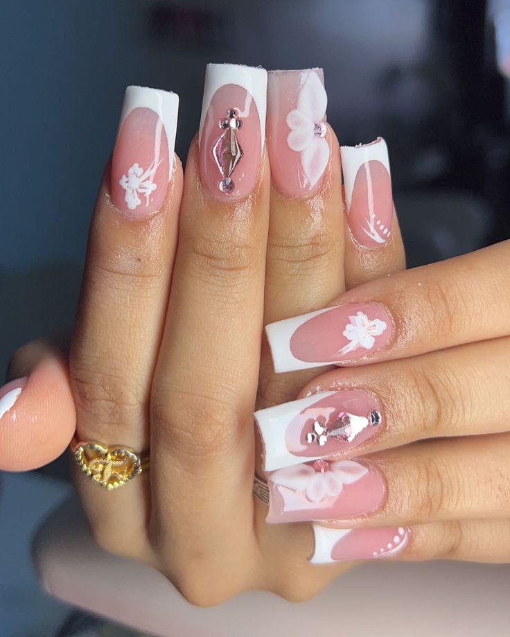 Elegant Soft Pink French Tip Nail Design with Floral Accents and Rhinestones.