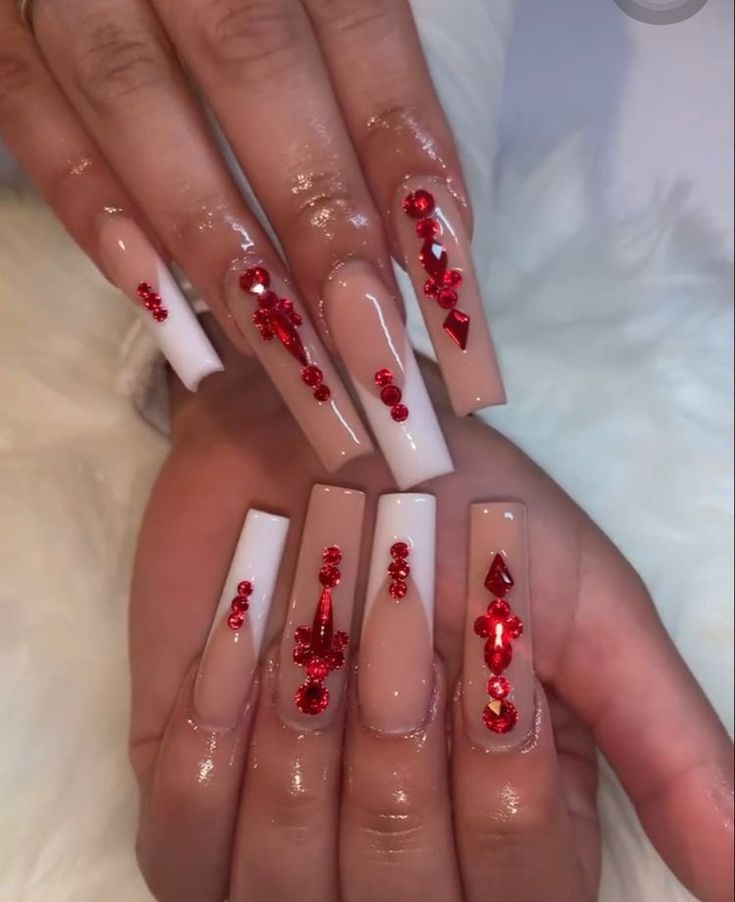 Elegant Long Acrylic Nails: Stunning Nude and White Tips with Glamorous Red Gemstone Accents.