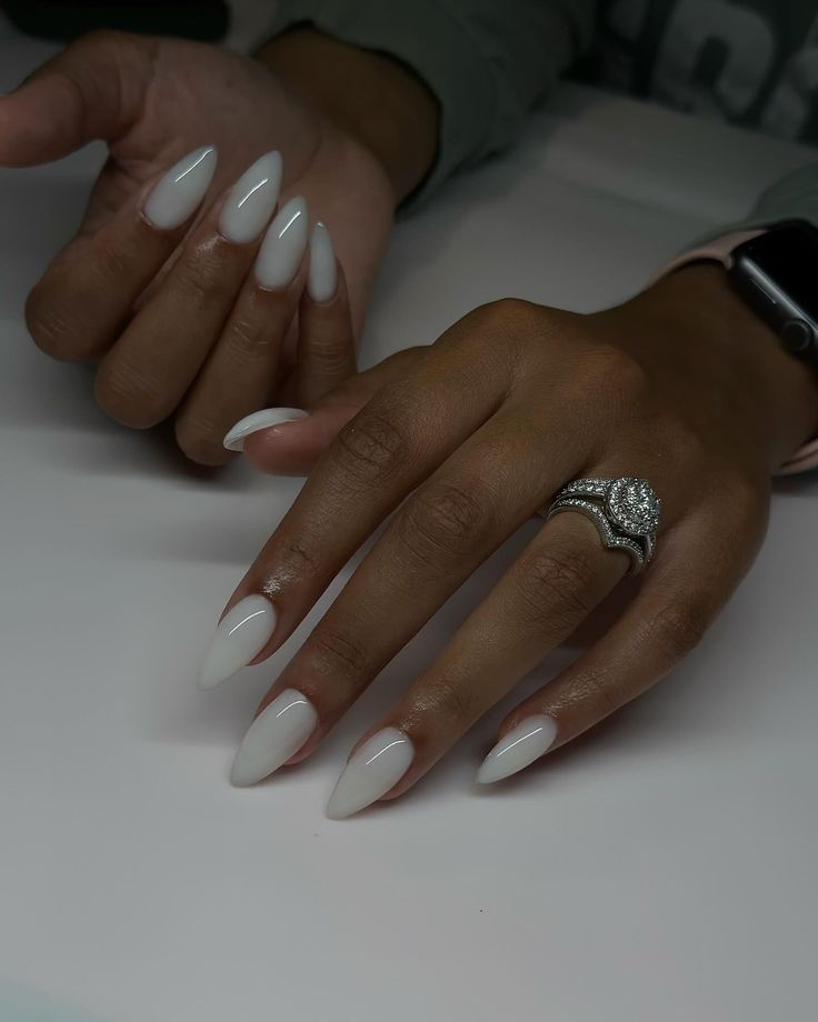 Chic Almond-Shaped Nails in Creamy White with Elegant Silver Ring: A Modern Minimalist Aesthetic.