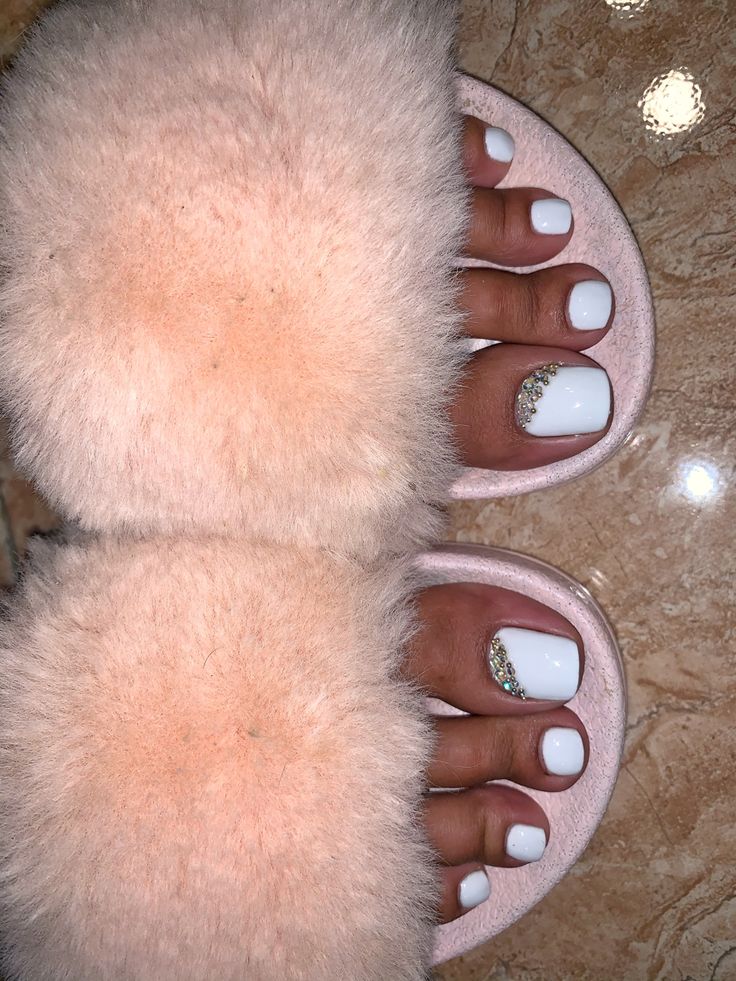 Chic White Toenails with Sparkling Accents: A Stylish Touch to Cozy Slippers and Casual Outfits.