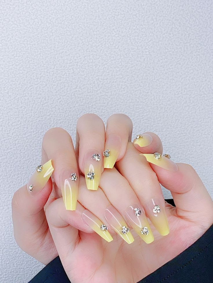 Glamorous Yellow Ombre Nails with Sparkling Rhinestones for a Striking Look.