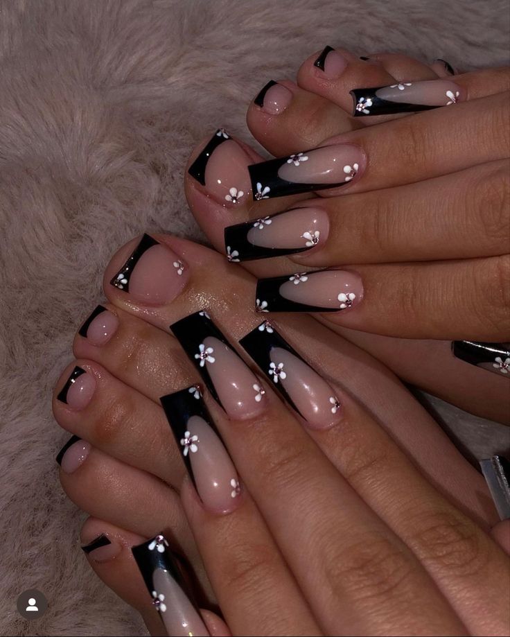 Elegant Black and Nude Nail Design with Delicate White Flower Accents