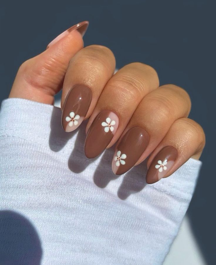 Chic Brown Almond Nails with Delicate White Floral Designs for Elegant Looks.