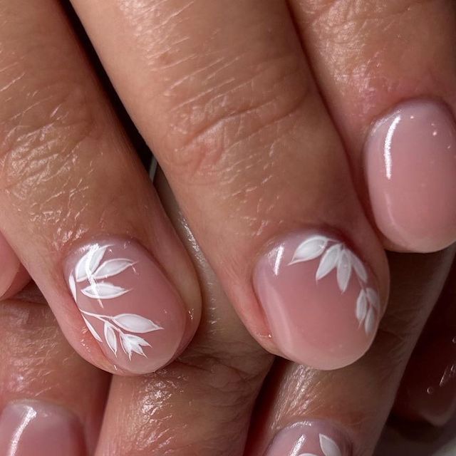 Elegant Nude Nail Art with White Leaf Designs for a Chic Look.