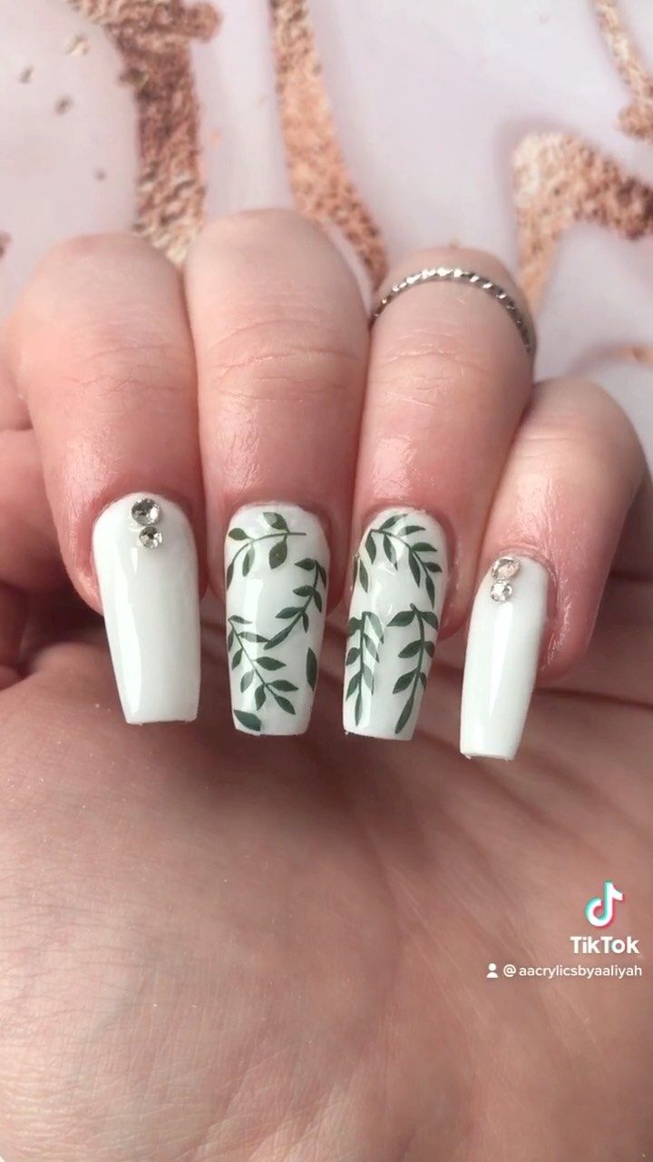 Chic White Nail Art with Delicate Green Leaves and Sparkling Rhinestones