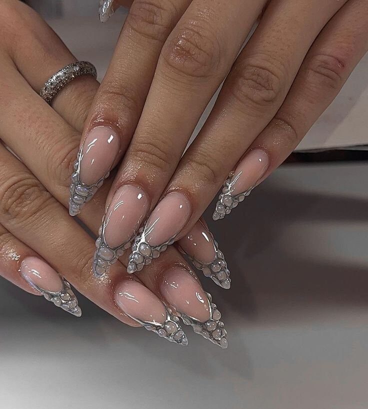 Chic Almond-Shaped Nails with Glossy Nude Base and Stunning Silver Accents.