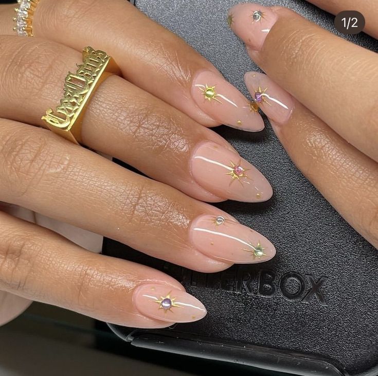 Chic Nude-Based Nail Design with Star Patterns and Sparkling Gems.