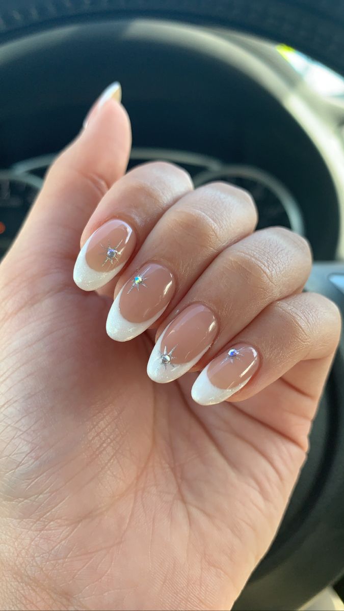 Chic French Tip Nails: Nude Base, Crisp White Tips, and Glamorous Rhinestone Accents.