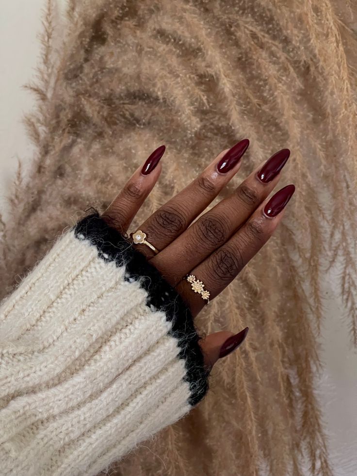 Chic Burgundy Almond Nails Paired with Cozy Sweater and Elegant Rings.