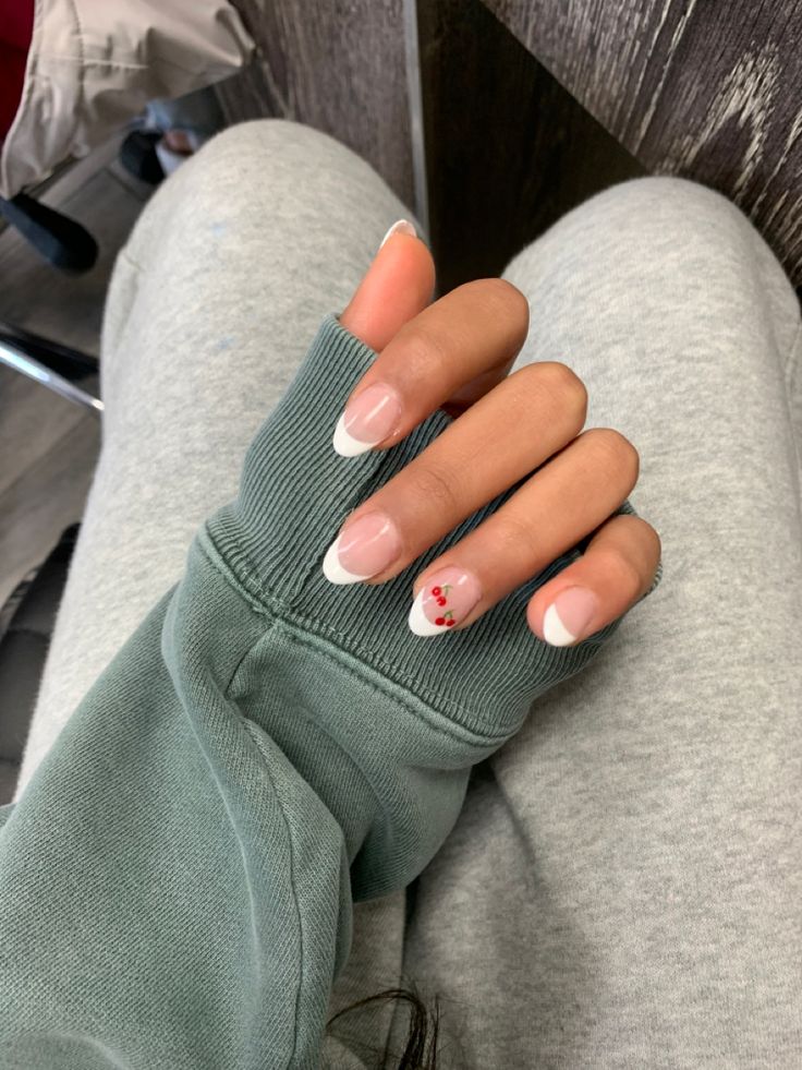 Chic French Manicure with Delicate Red Flower Accents and Cozy Gray Outfit.