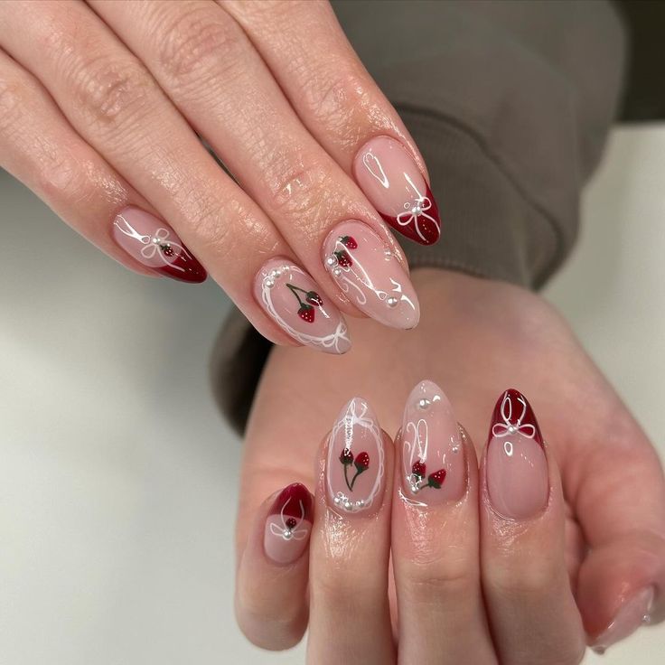 Chic Nail Design: Elegant Nude and Red Tones with Cherry Motifs and Glossy Finishes.