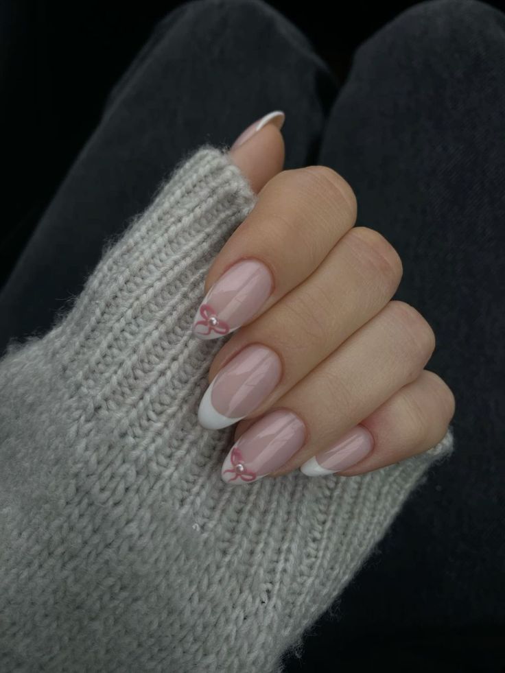 Chic Soft Pink Nail Design with Whimsical White Tips and Charming Bow Accents.