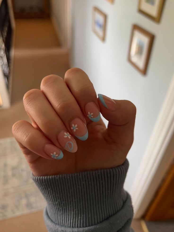 Elegant Nude and Light Blue Nail Art with Whimsical Floral Accents.