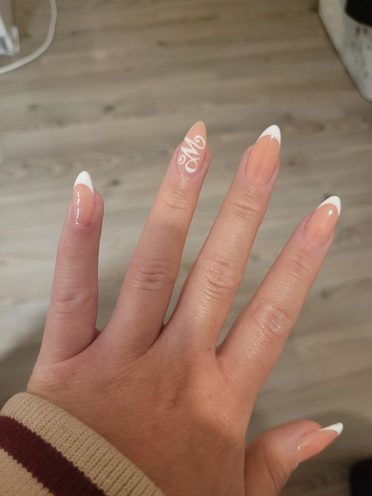 Chic French Manicure with Elegant Almond-Shaped Nails and Monogram Detail.