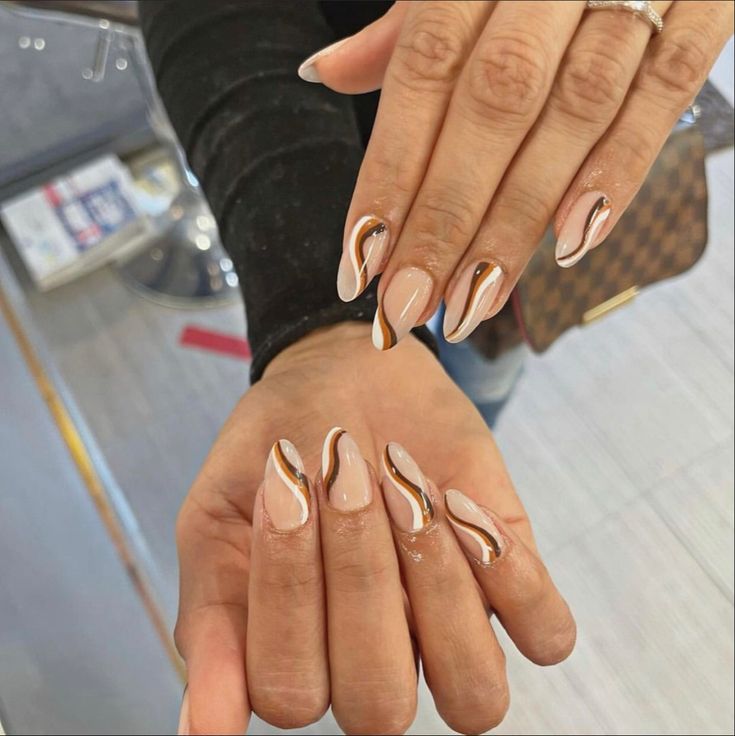 Chic Soft Nude Nails with Wavy Caramel and White Accents for a Sophisticated Look.