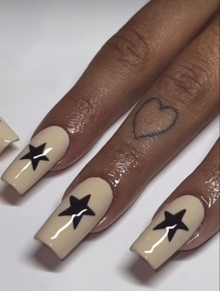 Chic Nude Nails with Bold Black Star Designs for a Modern Manicure.