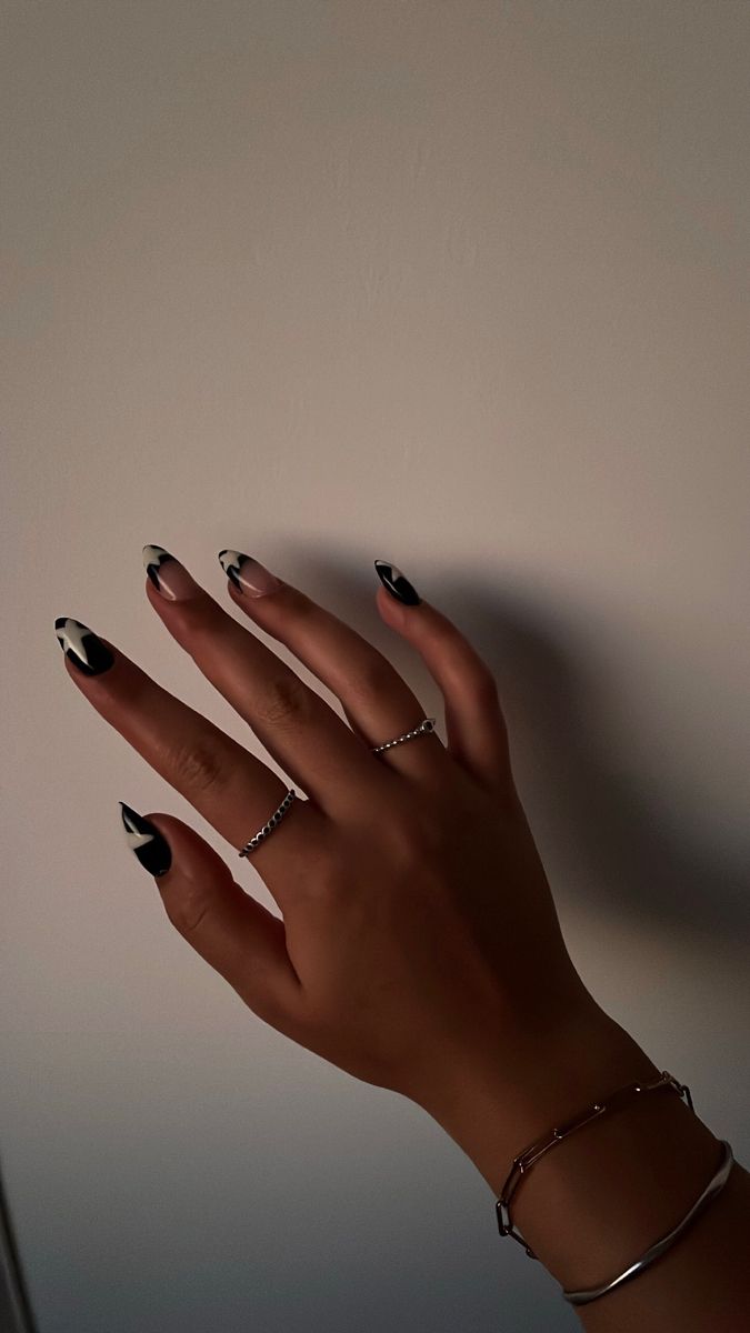 Sophisticated Black and White Stiletto Nail Design with Abstract Patterns and Silver Accents.