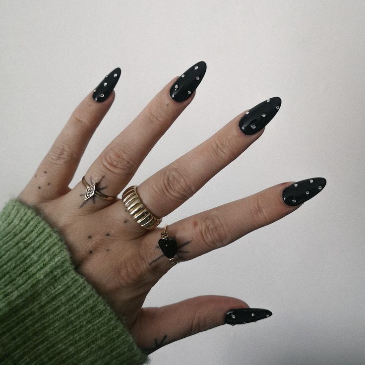 Chic Contrast: Edgy Black Rhinestone Nails Complementing a Cozy Green Sweater