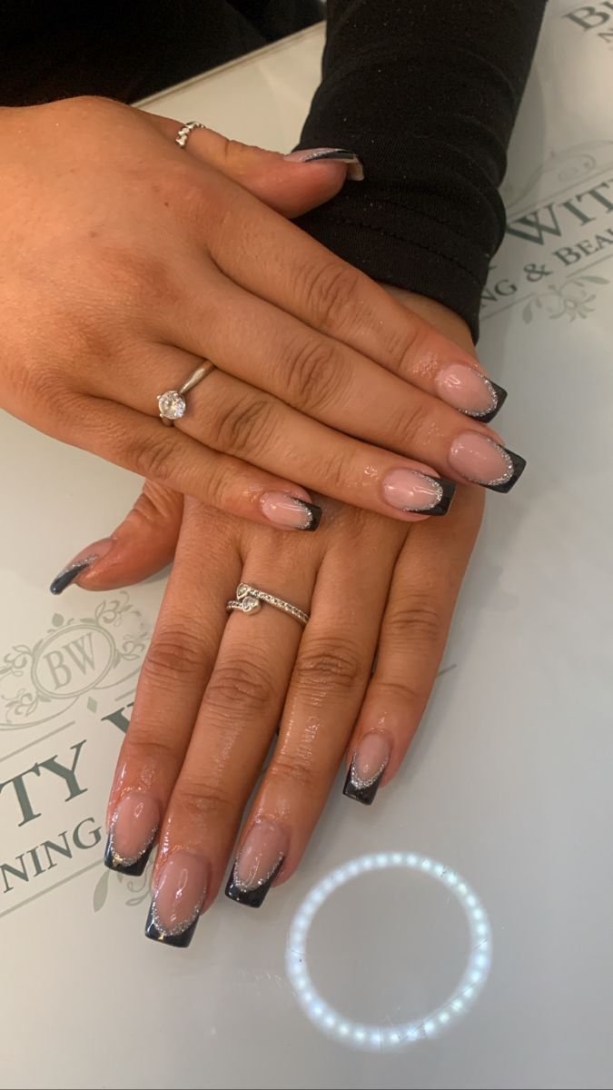 Sophisticated French Tip Manicure with Glossy Nude Base and Striking Black Tips.