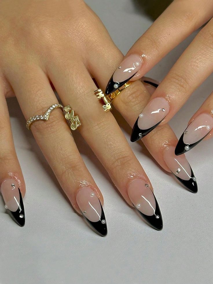 Chic Stiletto Nails: Nude Base with Bold Black Tips and Elegant Embellishments