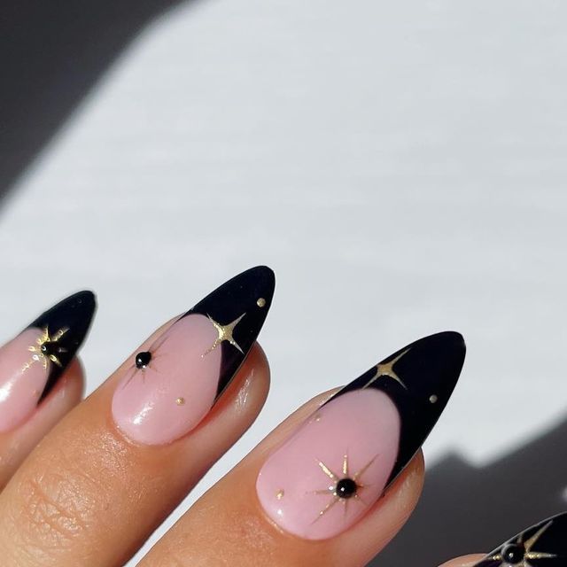 Celestial Elegance: Sophisticated Nail Design in Soft Pink and Deep Black with Gold Accents and Black Gems.