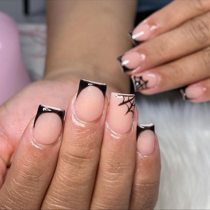 Chic French Tip Nails with Glossy Black Accents and Playful Spider Web Art.