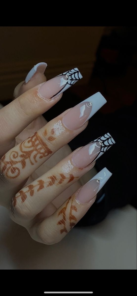 Chic Nail Art with Elongated Nude Acrylics, Sharp White Tips, and Black Spider Web Patterns Enhanced by Henna Designs.