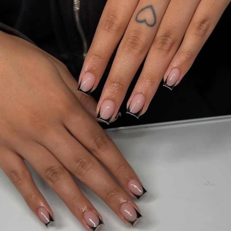 Modern French Manicure: Chic Nude Base with Bold Black Tips and Heart Tattoo Accent.