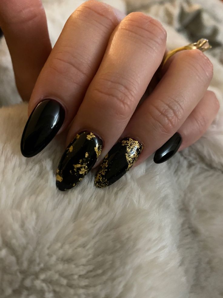 Luxurious Almond-Shaped Black and Gold Nail Design: A Perfect Blend of Boldness and Sophistication.