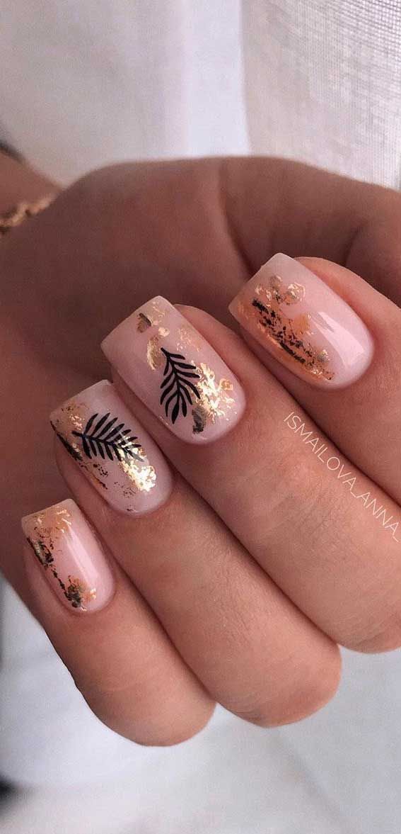 Sophisticated Nude Nail Design with Shimmering Gold Accents and Delicate Black Leaf Patterns.