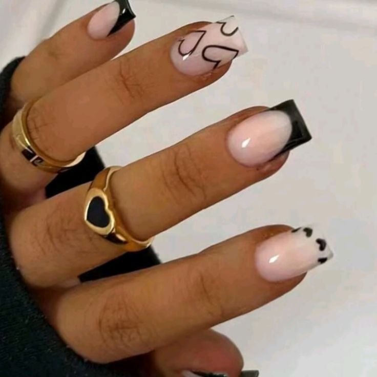 Chic Nail Design: Soft Pink and Bold Black with Heart Patterns and Gold Accents.