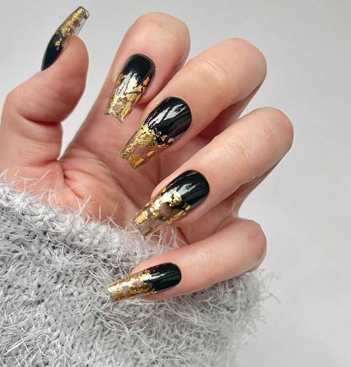 Glamorous Gradient: Deep Black and Shimmering Gold Nail Design.