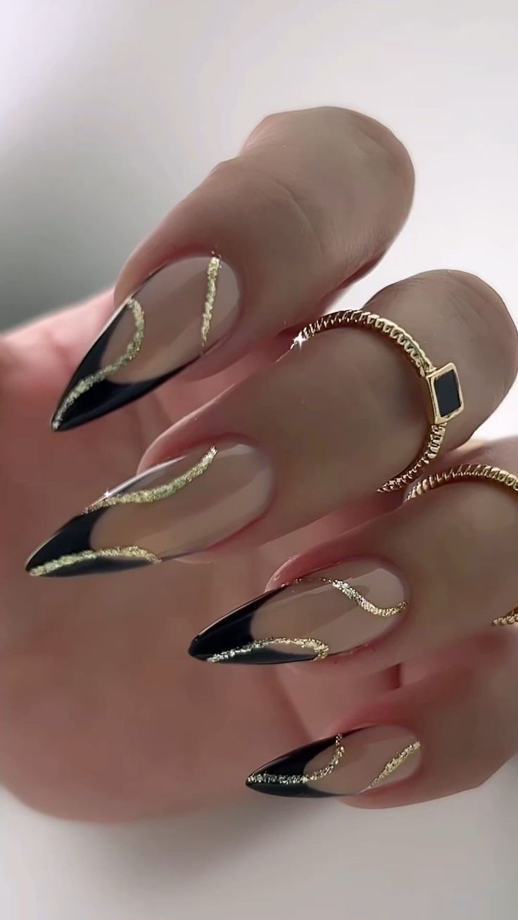 Chic Elegant Stiletto Nails: Black Tips and Gold Accents on a Nude Base.