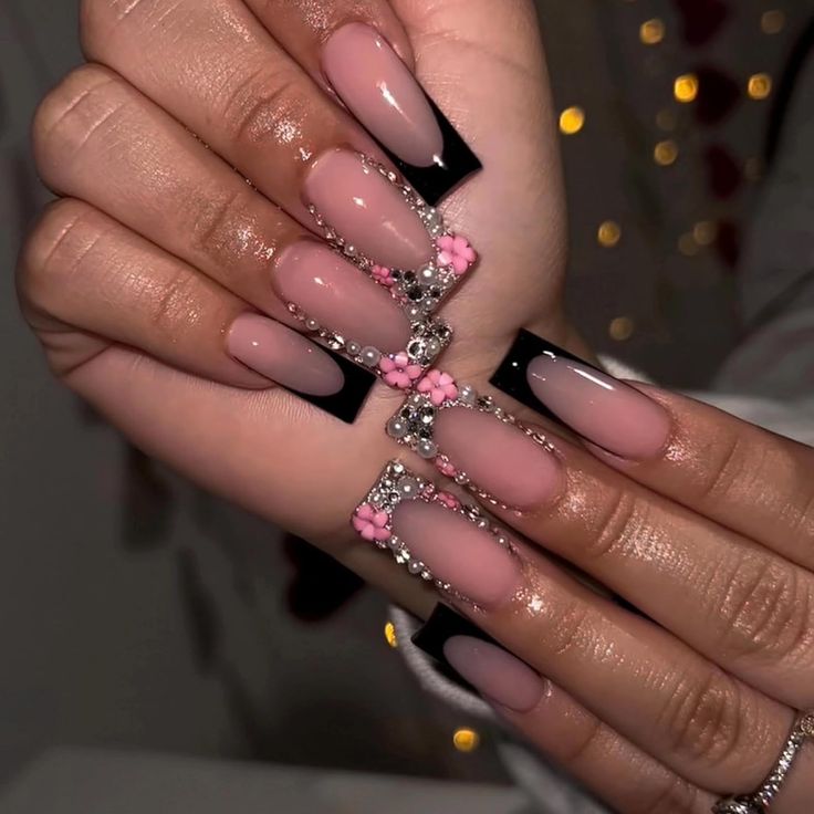 Chic Nude and Black Nail Design with Elegant Pink Floral Accents.