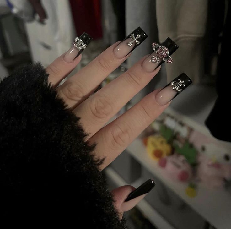 Chic Modern French Nail Design: Elongated Tips with Nude Base, Black Tips, and Intricate Embellishments.