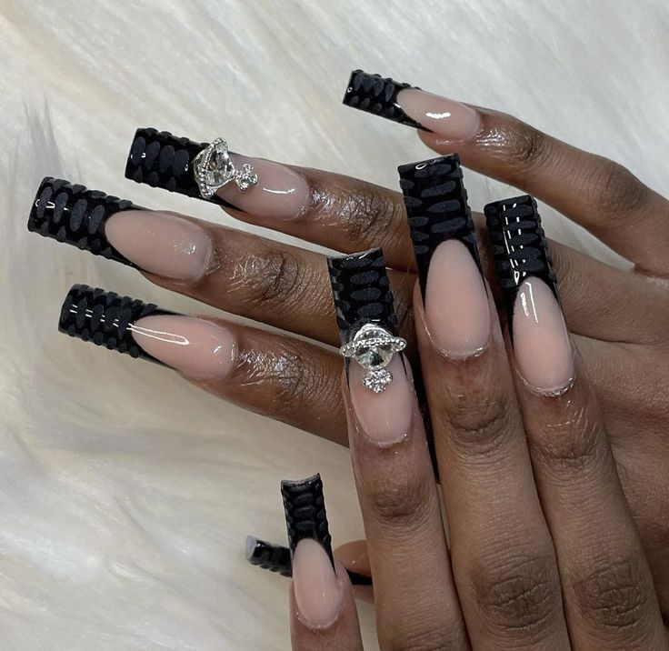 Elegant Nude and Black Textured Long Nails with Bold Patterns and Embellishments.