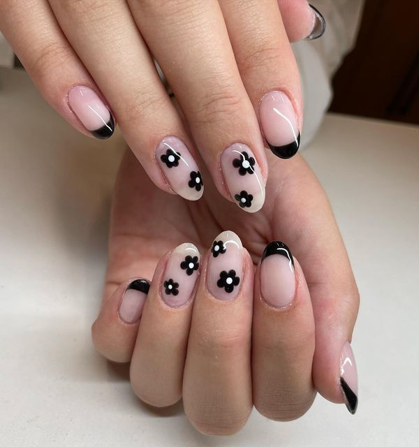 Sophisticated Nude Nail Design with Black Floral Accents and Classic French Tips.