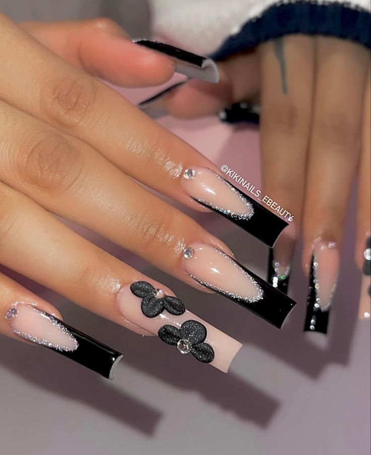 Sophisticated Nude and Black Nail Design with French Tips and Decorative Floral Accents