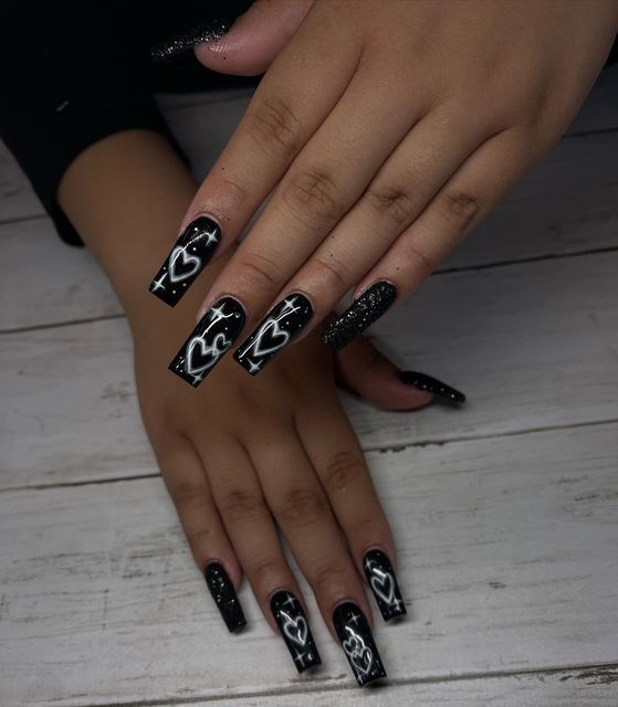 Chic Black Acrylic Nails with Matte and Glitter Finishes Highlight Playful Heart Designs.