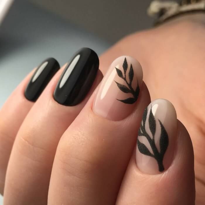 Chic Nail Design: Elegant Black Leaf Patterns on Glossy Black and Nude Bases.