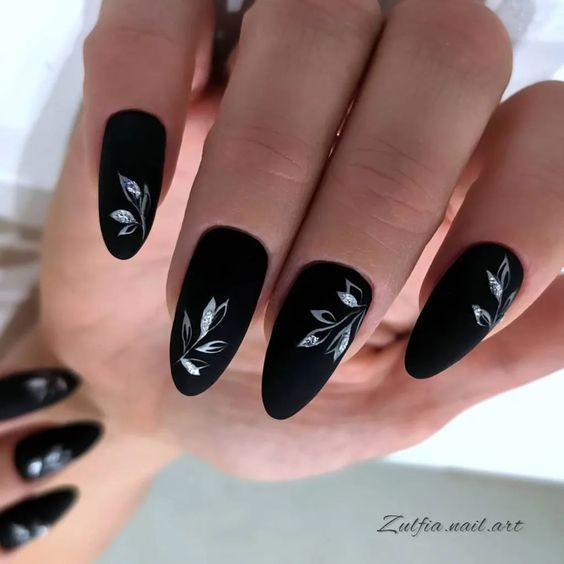 Striking Elegant Black Matte Nails with Intricate Silver Leaf Designs.