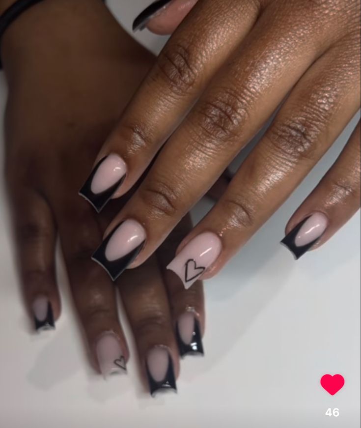 Elegant Nail Design: Soft Nude Base with Bold Black Tips and Playful Heart Accents.