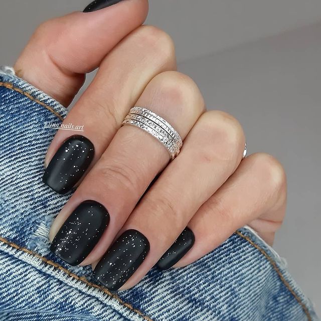 Chic Matte Black Nail Design with Shimmering Accents and Stylish Accessories