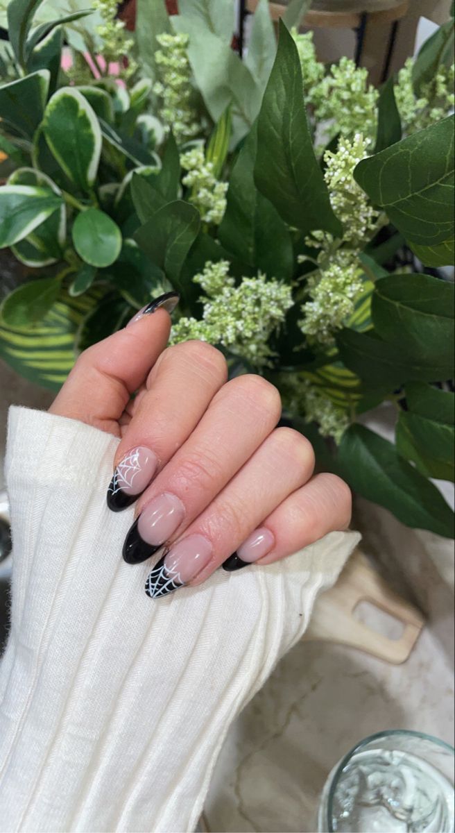 Chic Nude and Black Nail Design with Delicate White Spiderweb Patterns.