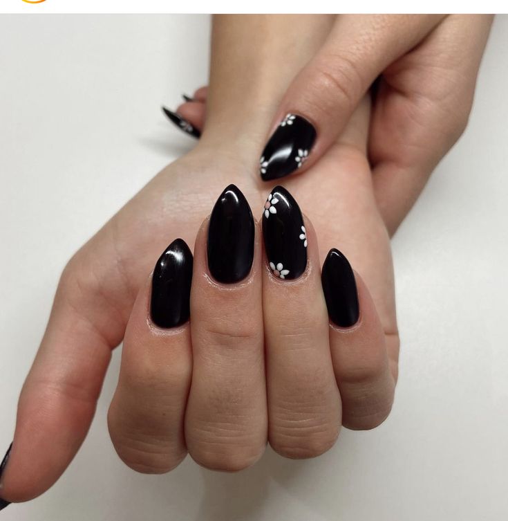 Sophisticated Black Pointed Tip Nails with Glossy Finish and Delicate White Floral Accents.