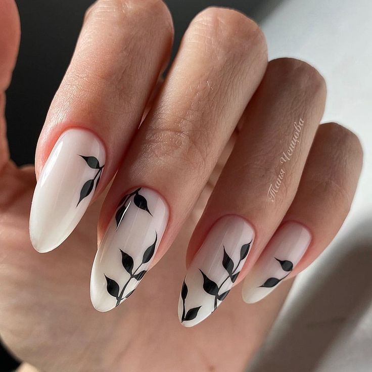 Chic Minimalist Nail Design: Soft White Base with Delicate Black Leaf Patterns