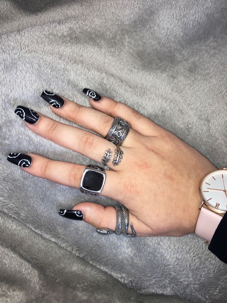 Elegant Black Nails with Artistic White Designs and Silver Accents for a Chic Look.