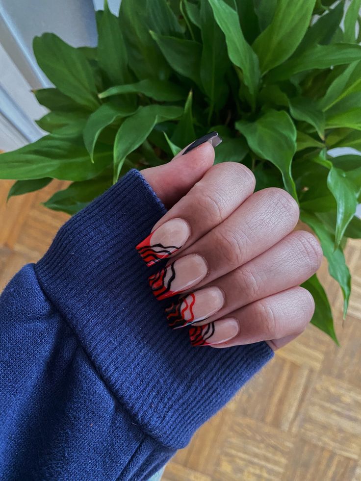 Chic Nail Design: Elegant Nude Base with Bold Red and Black Wavy Lines.